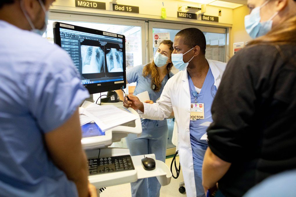 Rachel Muster (third from right), a medical student at UCSF, looks at a lung scan during rounds in the COVID-19 Intensive Care Unity at UCSF Medical Center at Parnassus Heights. The team includes Saned Raouf (left), MD, Brandon Scott (center), MD, MBA, and Alexandra Hill, MD. Photo by Susan Merrell