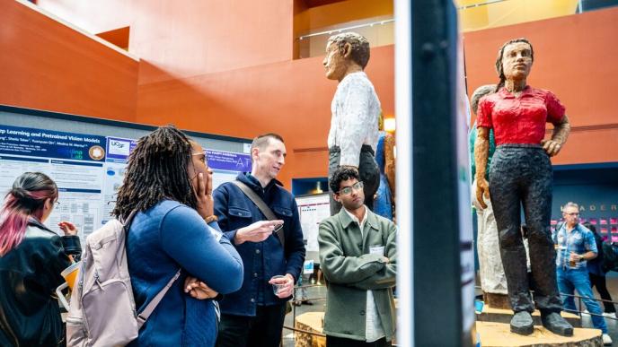 UCSF Professor Tony Capra, PhD, center, examines a poster during Research AI Day at UCSF’s Mission Bay campus on Monday, March 17, 2025. (Photo by Noah Berger)
